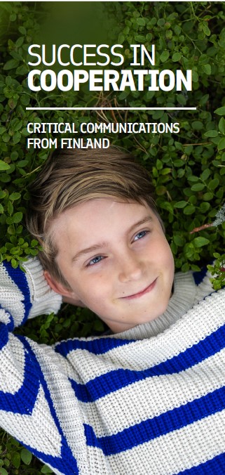 Critical Communications Finland eBooklet cover picture. Pre-Teen boy smiling whilst lying on the grass hands behinds his head. He wears a horizontally blue and white striped pull over